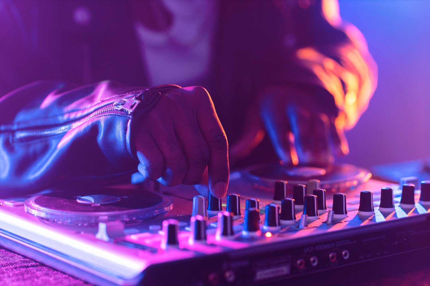 DJ in consolle durante una sessione di breakdance con luci colorate